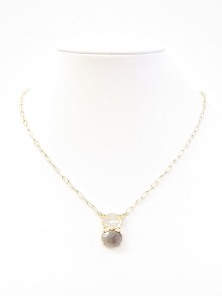 Gold layered necklace with clear crystal and gray stone pendant on white background