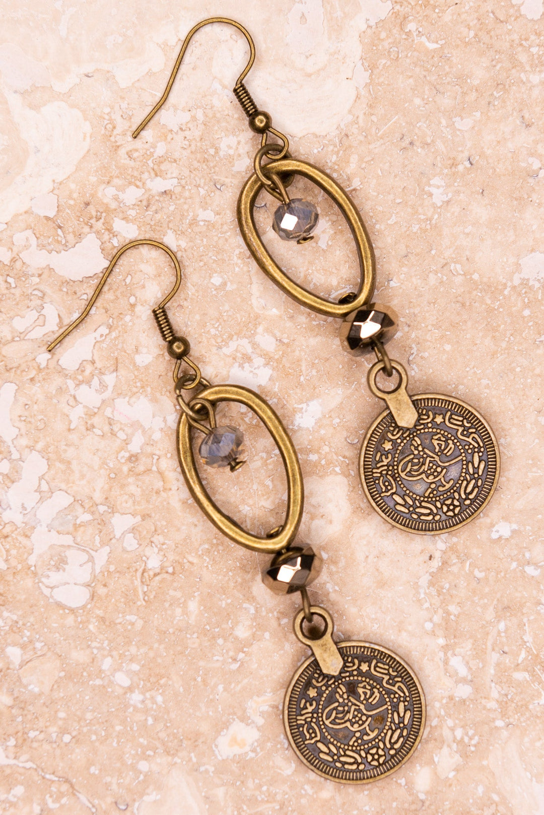 Antique bronze coin drop earrings with oval hoop and crystal beads on marble surface