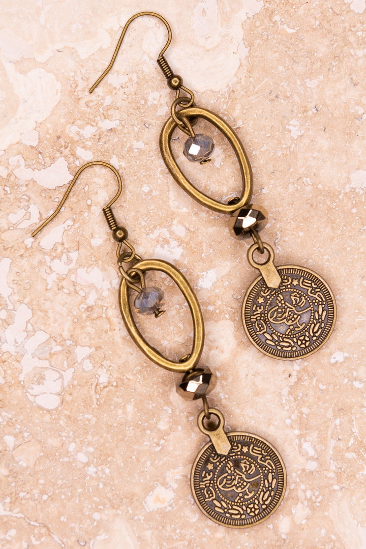 Antique bronze coin drop earrings with oval hoop and crystal beads on marble surface