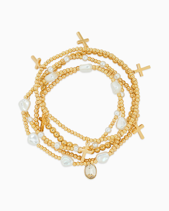 Set of five gold beaded stretch bracelets with cross charms, pearls, and crystal pendant