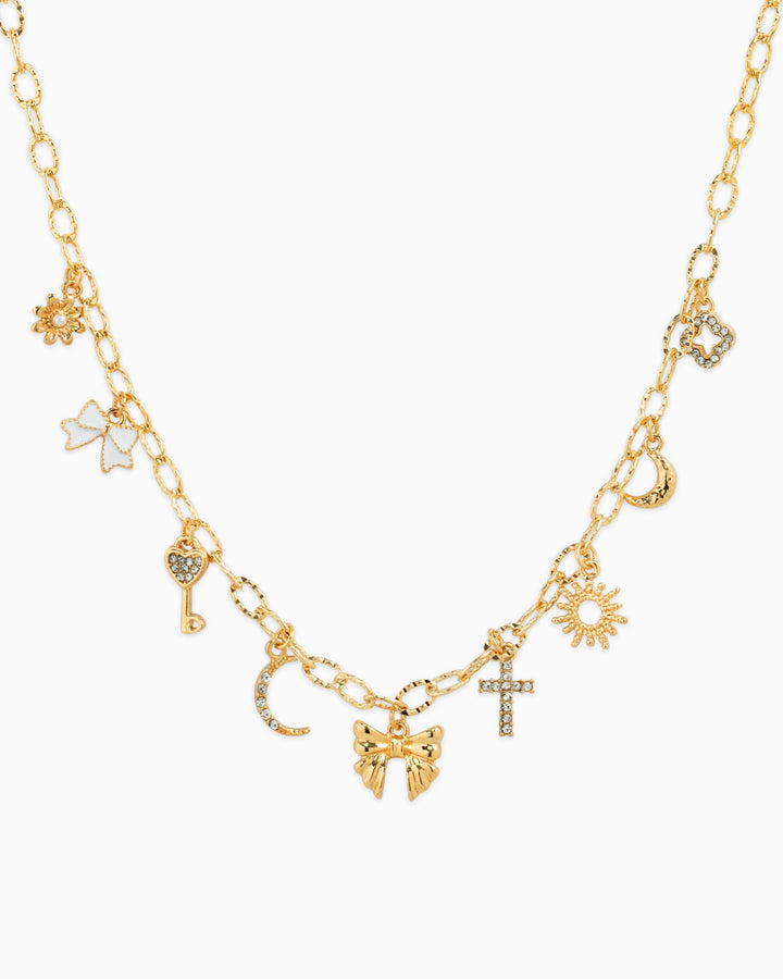 Gold multi-charm necklace featuring bow, sunburst, cross, moon, key, and floral charms