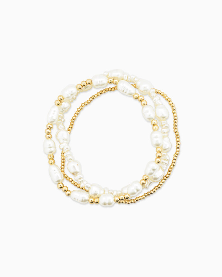 Set of three stretch bracelets featuring white freshwater pearls and gold beads