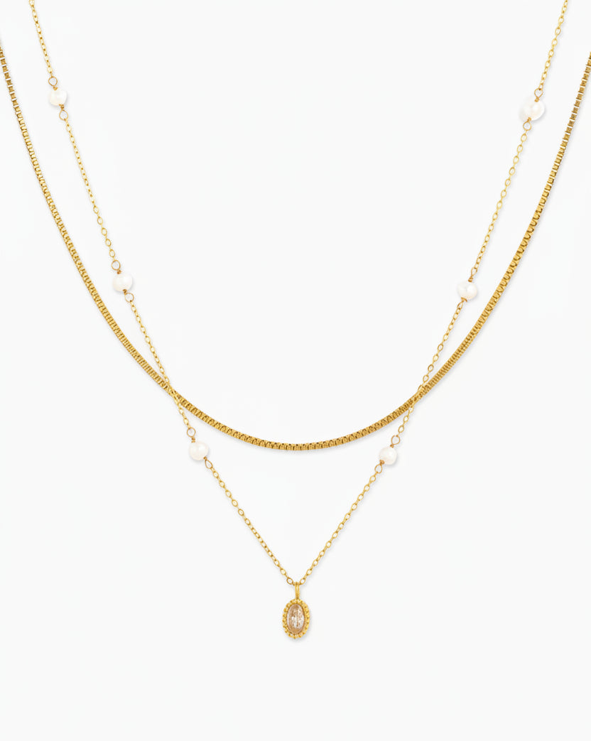 Gold double-layered necklace featuring pearl accents and an oval crystal pendant