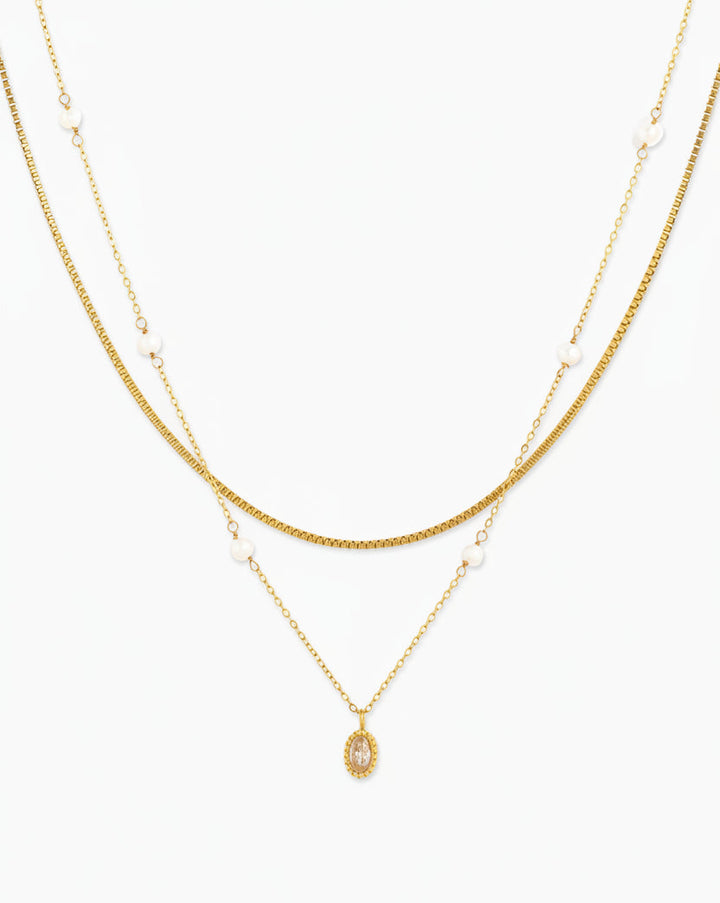 Gold double-layered necklace featuring pearl accents and an oval crystal pendant
