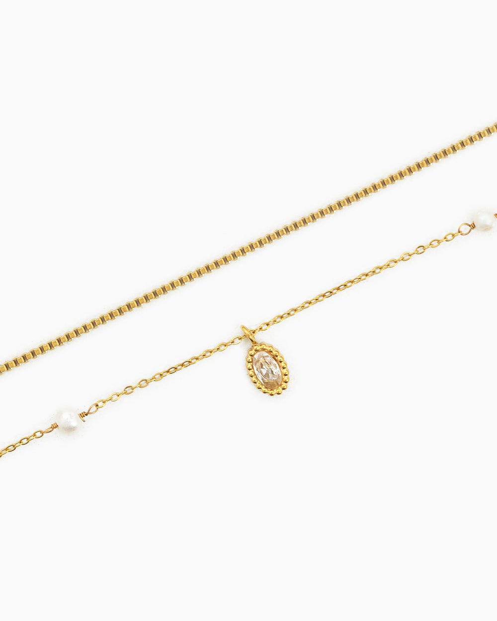 Gold double-layered necklace featuring oval crystal pendant, small white freshwater pearls, and box chain