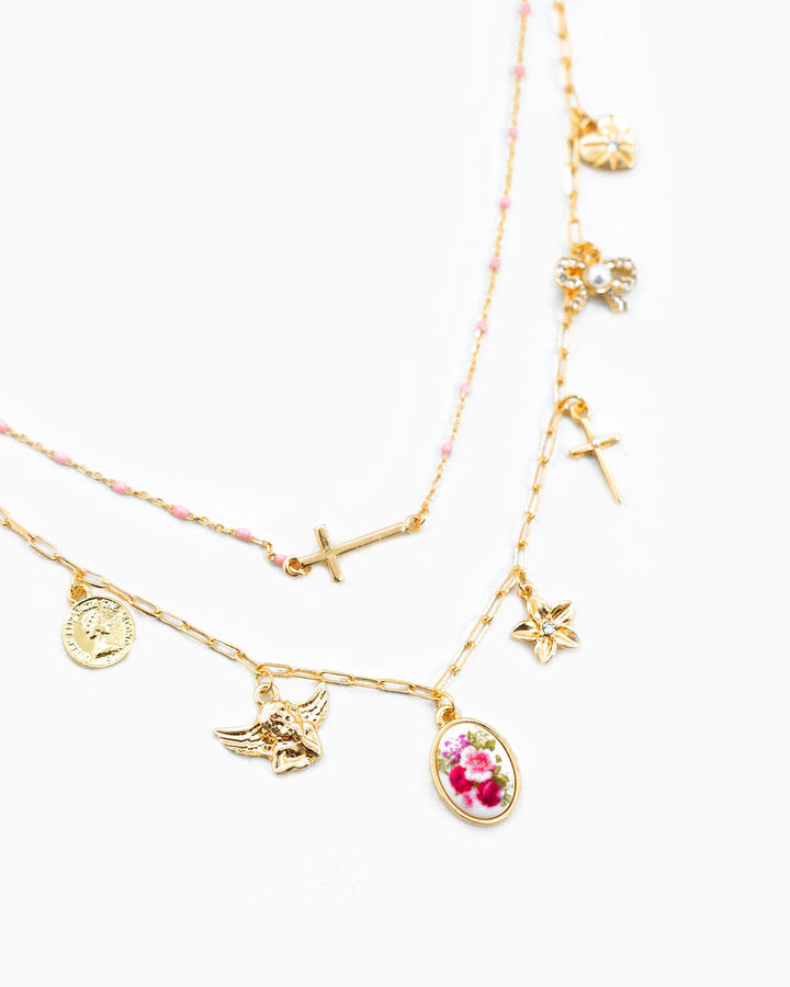 Sessori gold layered charm necklace featuring cross, angel, floral cameo, and star pendants