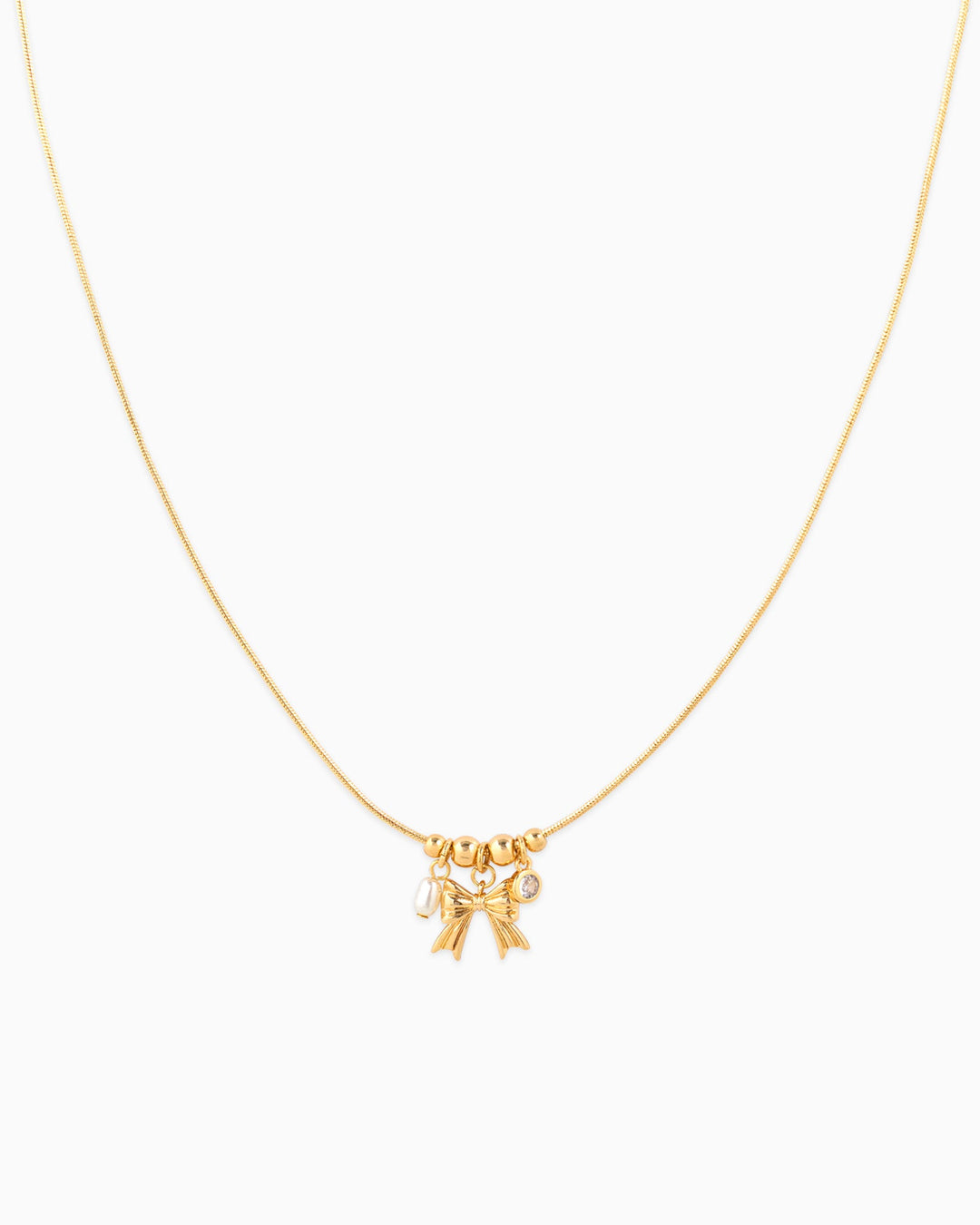 Dainty gold necklace with bow charm, small pearl, and crystal accent pendants