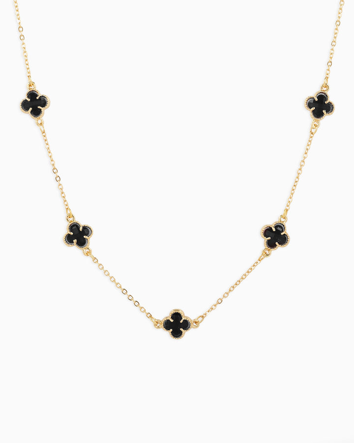 Gold chain station necklace featuring five black clover-shaped pendants evenly spaced.