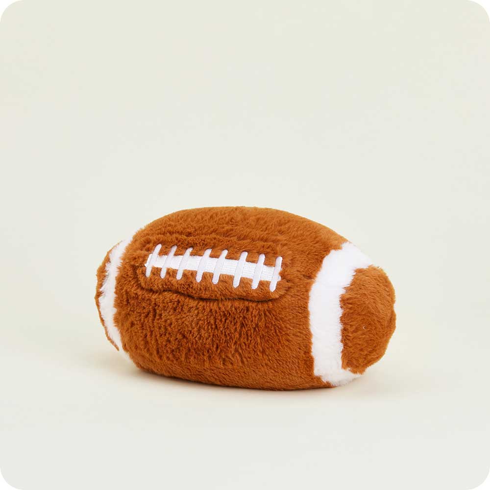 Warmies football-shaped plush toy with brown fabric and white laces against neutral background