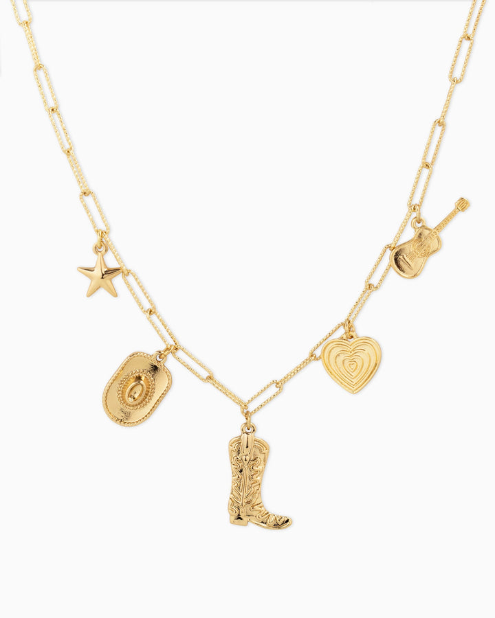 Gold charm necklace featuring western icons: star, cowboy hat, boot, heart, and guitar charms.