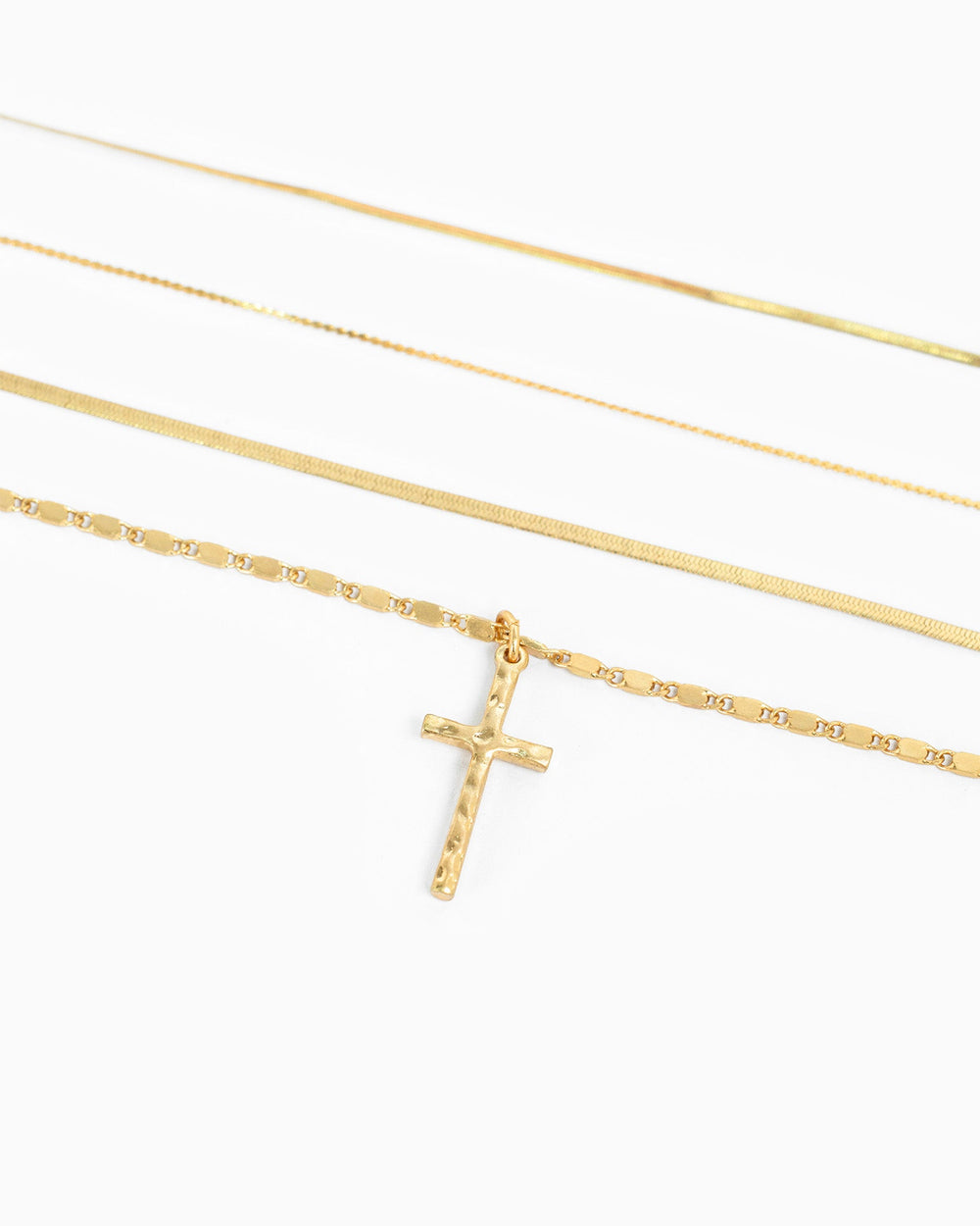 Gold 4-layered snake chain necklace set with hammered cross pendant on white background.