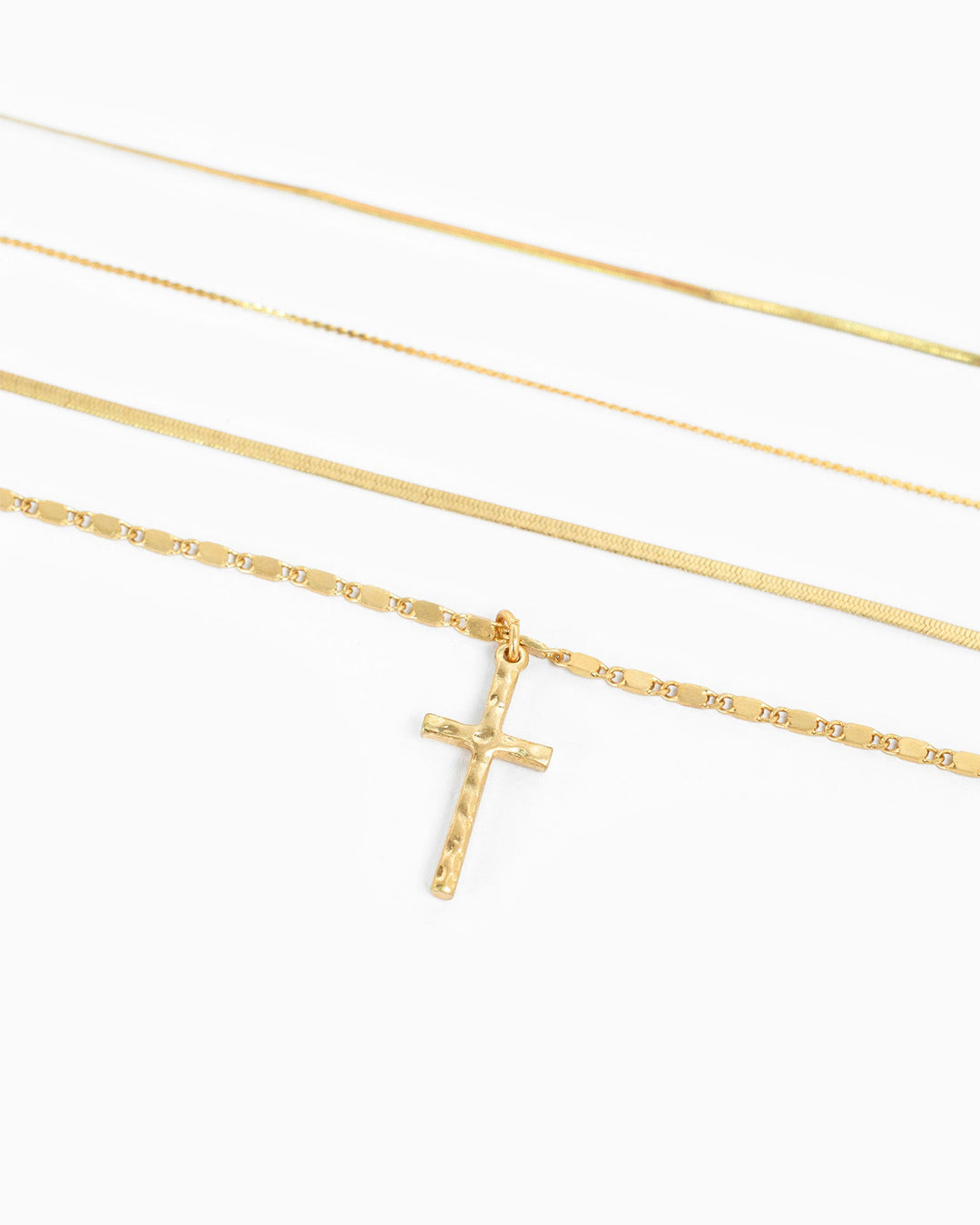 Gold 4-layered snake chain necklace set with hammered cross pendant on white background.