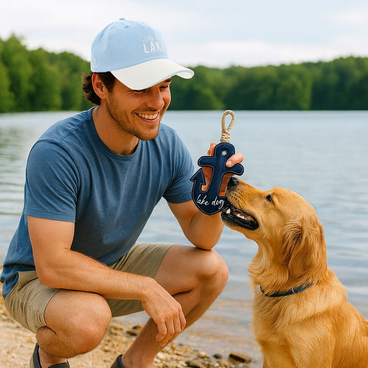 Navy blue anchor-shaped dog toy with rope handle being held by man with golden retriever
