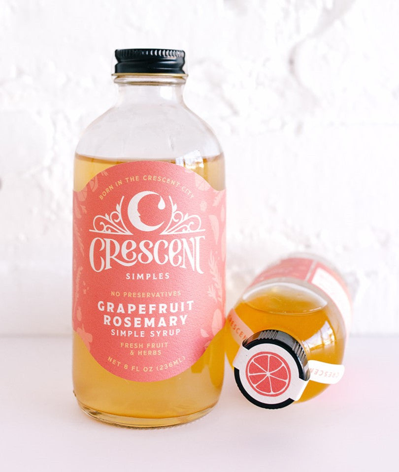 Crescent Simples Grapefruit Rosemary Simple Syrup bottle with amber liquid and coral pink label