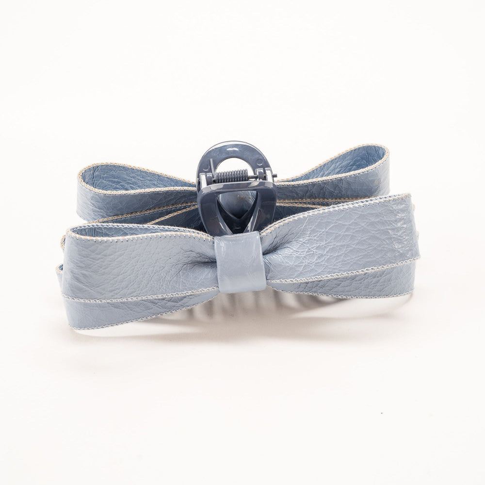 Gray-blue leather bow hair clip with metal clasp on white background