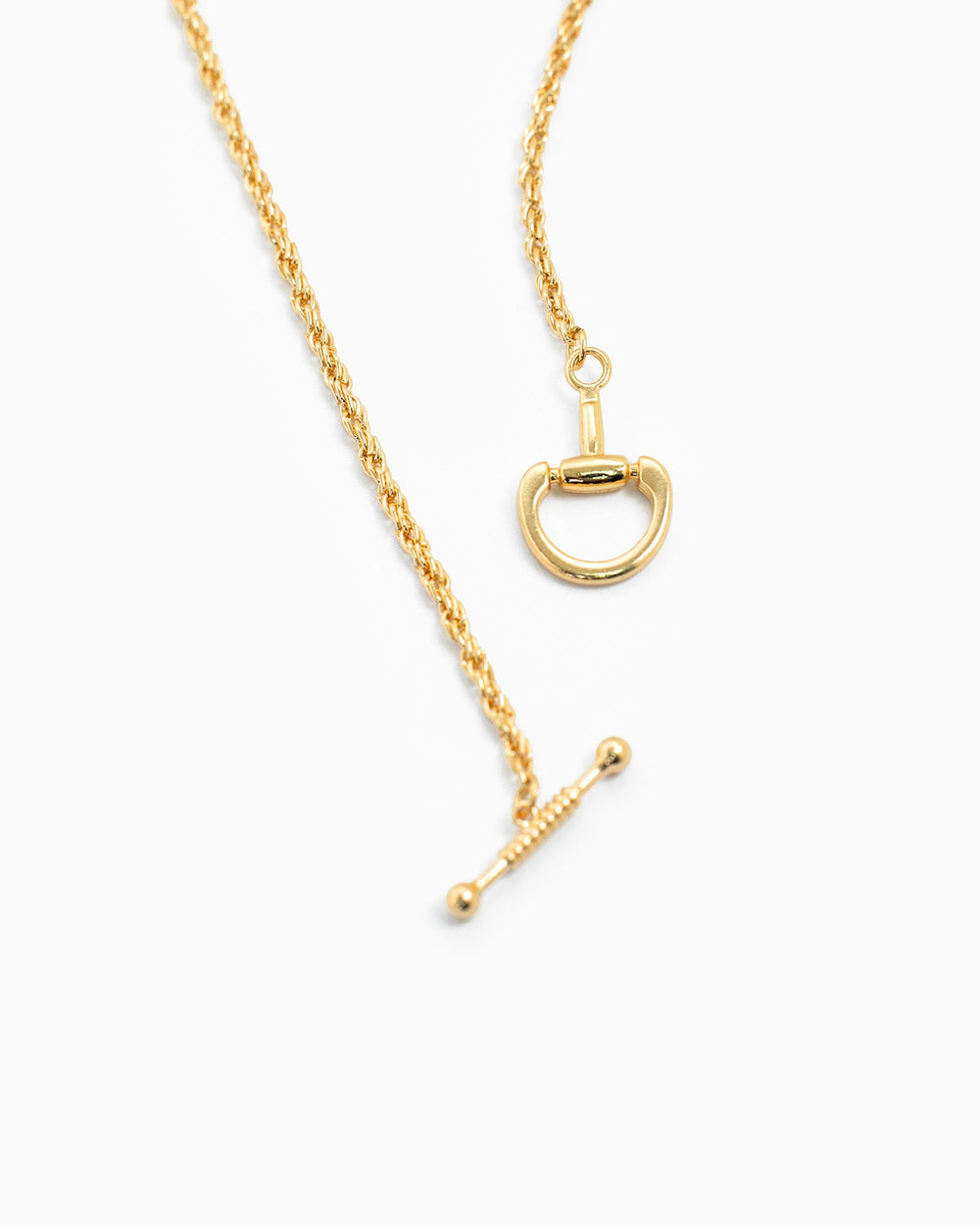 Gold horsebit toggle rope chain necklace with decorative clasp on white background.