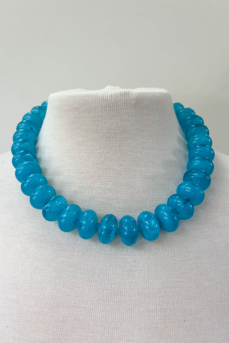 Chunky turquoise blue resin bead necklace displayed on white jewelry bust