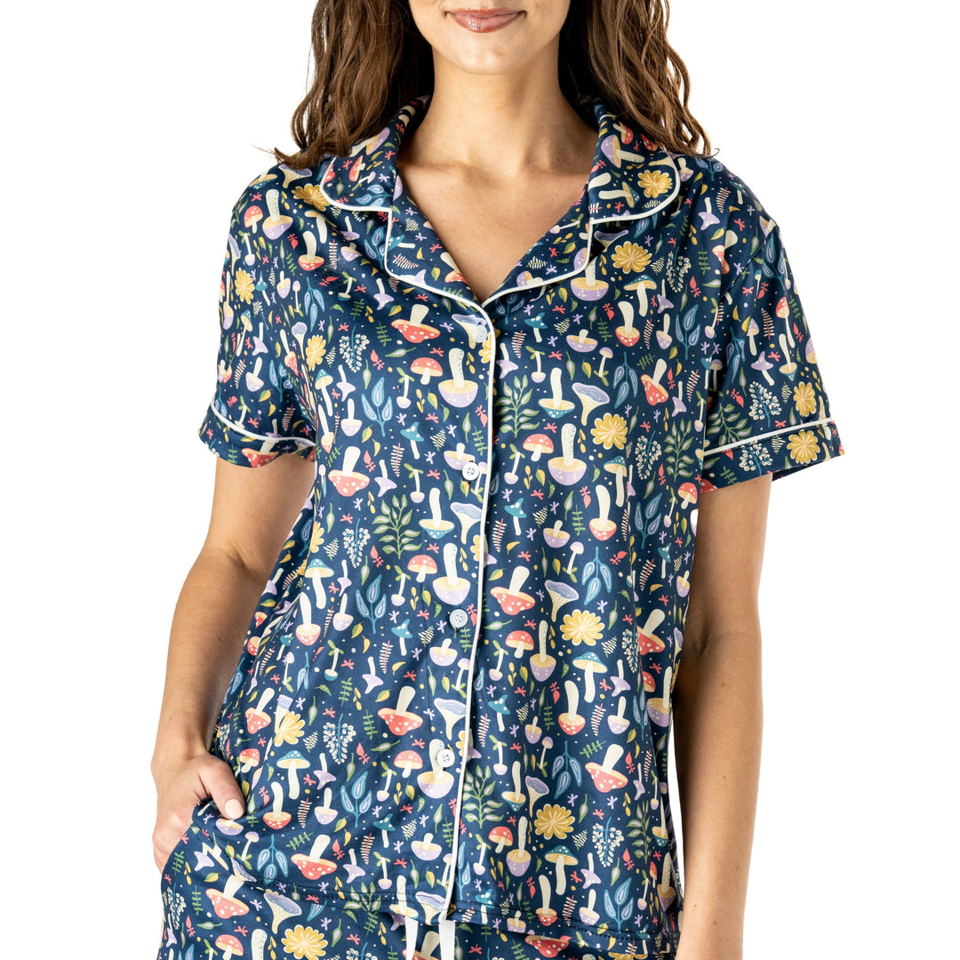 Woman wearing navy pajama top with colorful mushroom and botanical print pattern