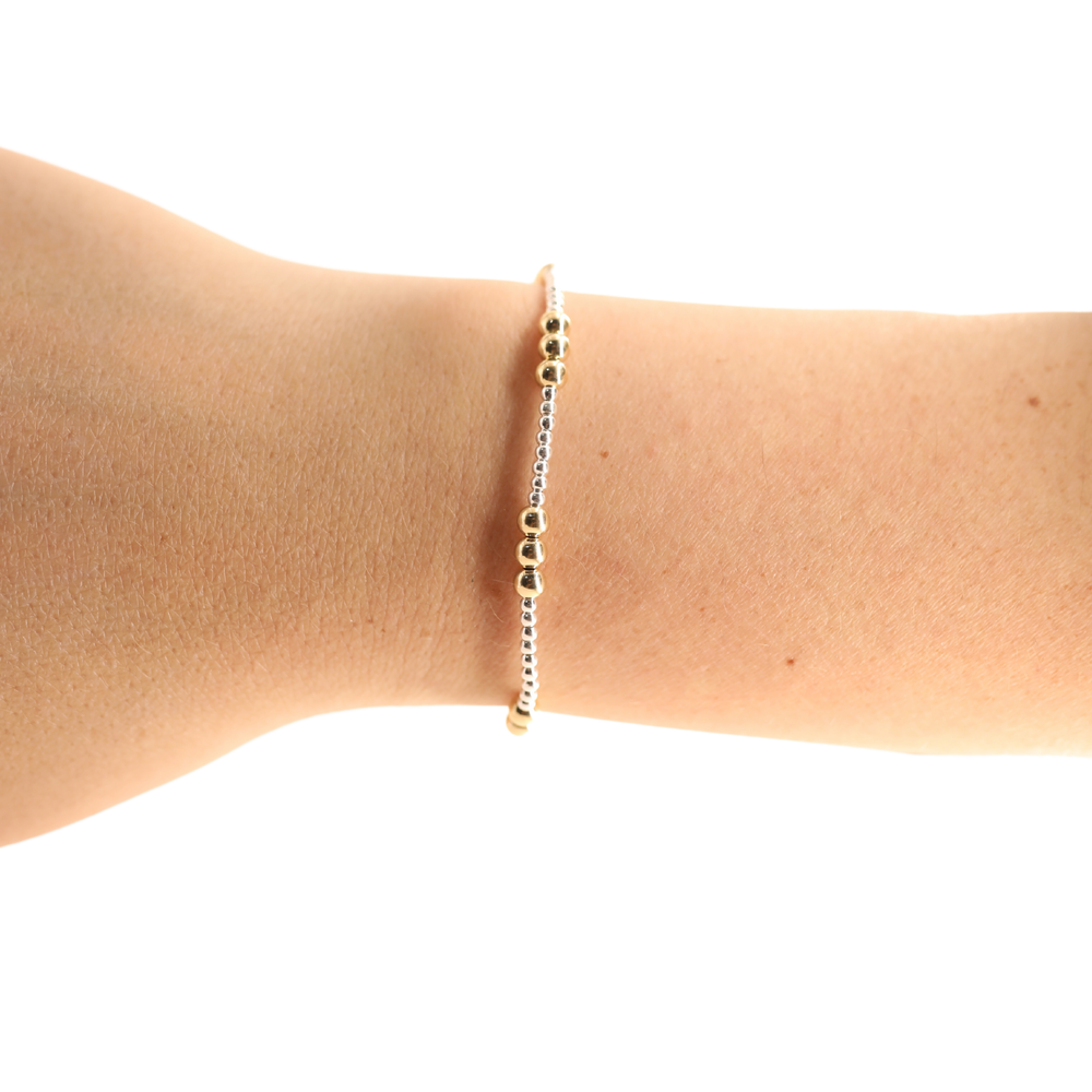 Dainty beaded bracelet with mixed gold and silver beads worn on a wrist
