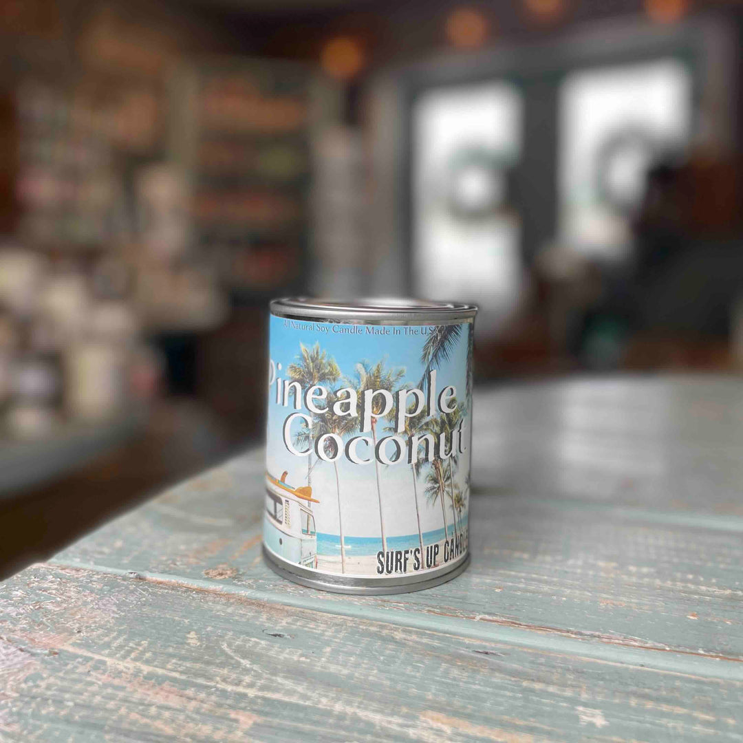 Surf's Up Candle Pineapple Coconut paint can candle in tin on rustic wooden surface.