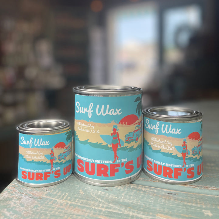 Surf Wax Paint Can Candle in three sizes with retro beach-themed teal label on rustic surface.