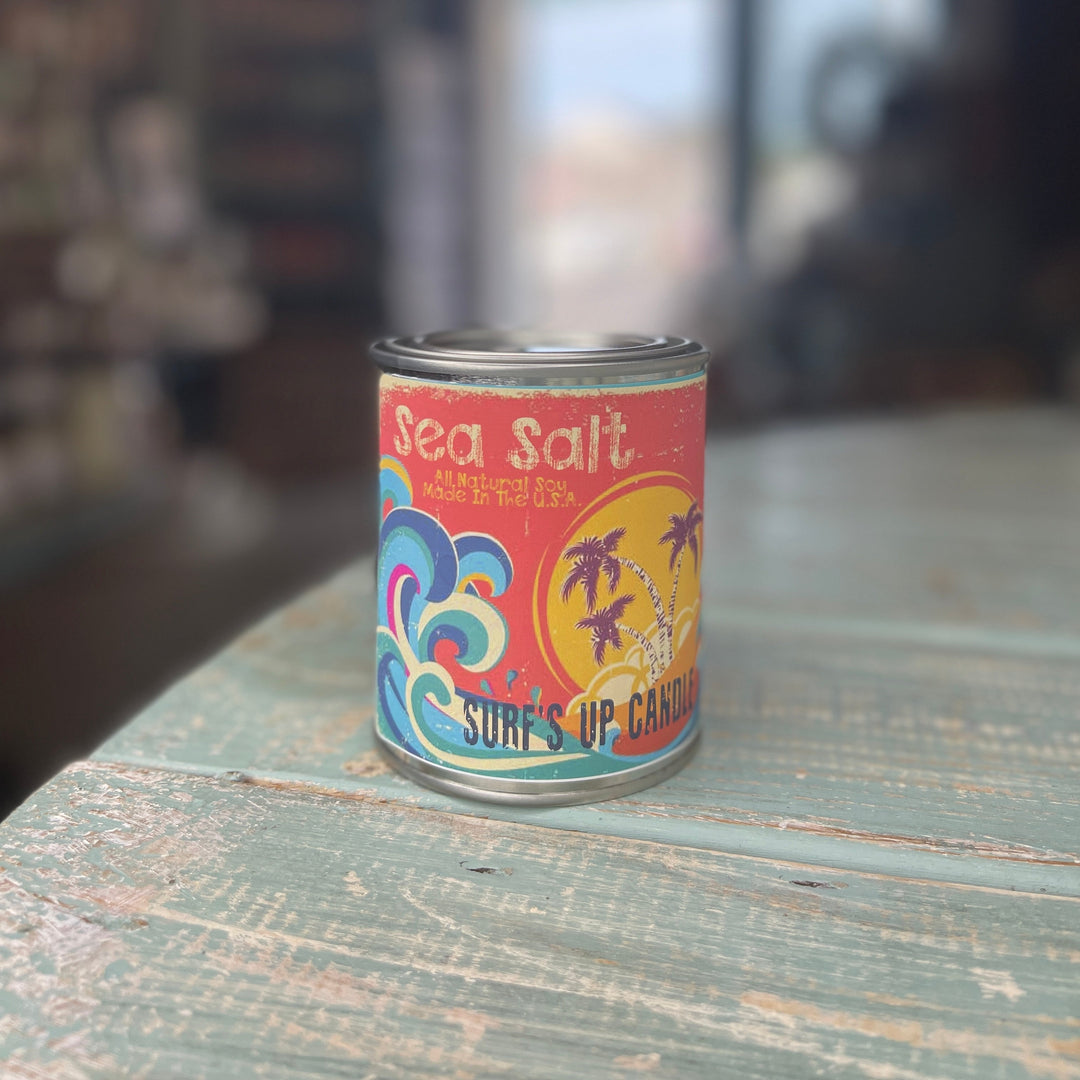 Surf's Up Candle Sea Salt paint can candle with tropical beach label on rustic wooden surface.