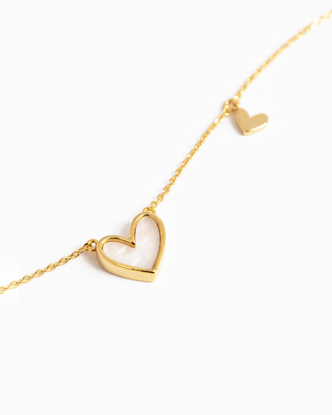 Gold asymmetrical necklace with large mother-of-pearl heart pendant and small solid gold heart charm