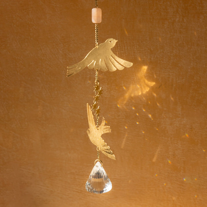 Gold bird suncatcher with crystal prism hanging ornament creating rainbow light reflections