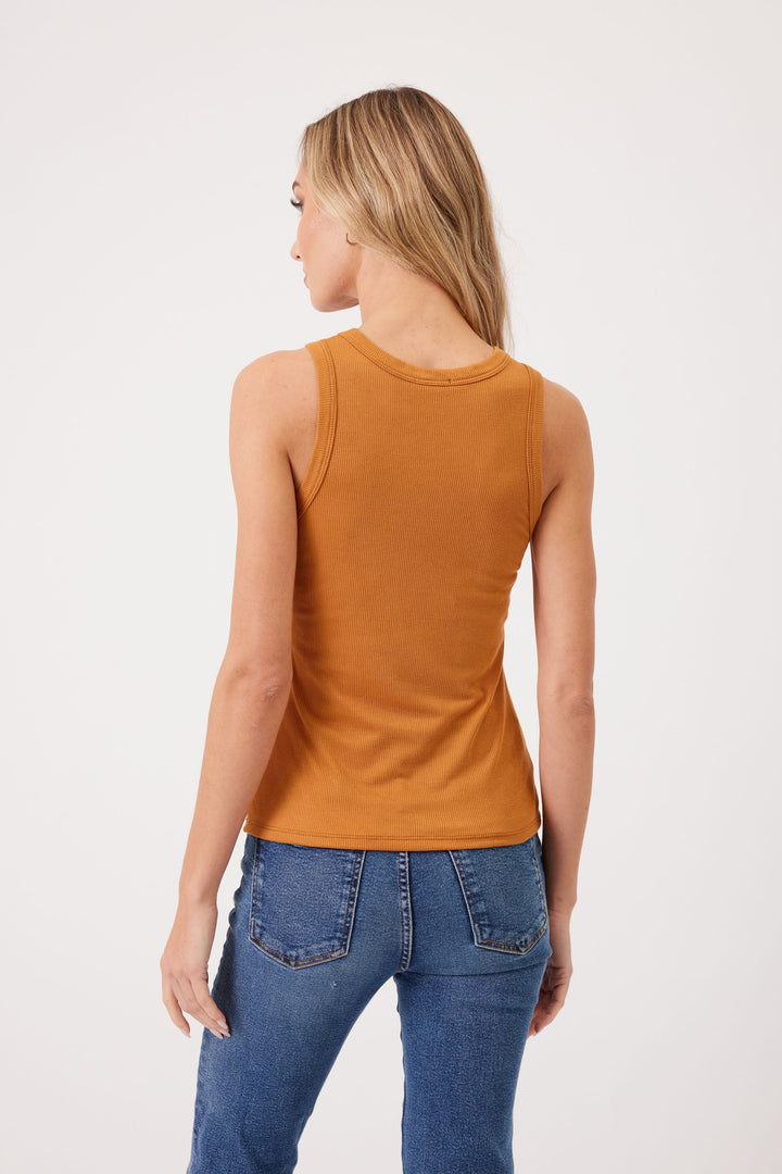 Woman wearing mustard ribbed sleeveless tank top with blue jeans, back view