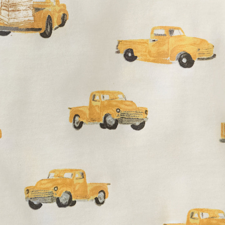 Close-up fabric detail showing repeating yellow vintage pickup truck pattern on cream background