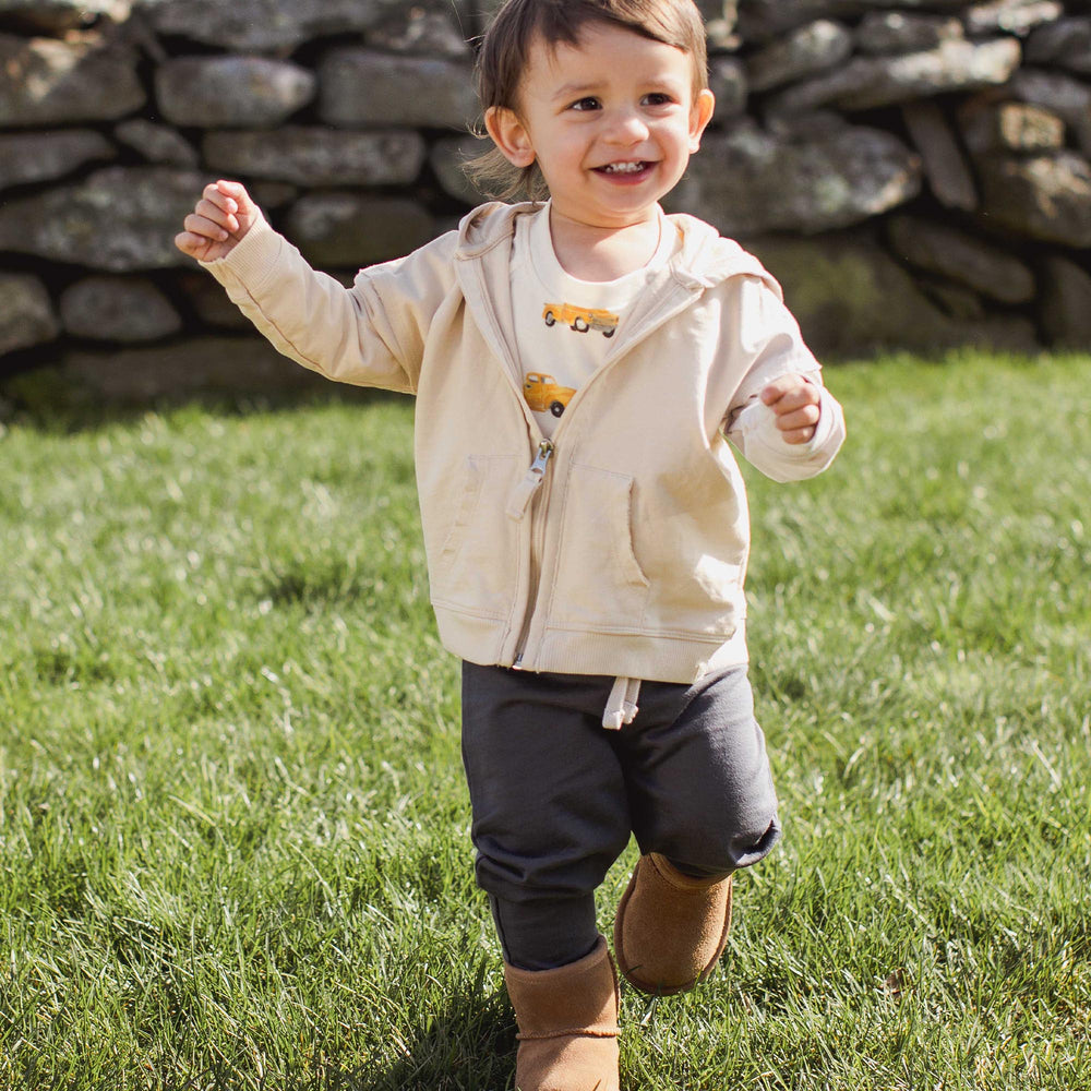 Toddler running outdoors wearing Burt's Bees Baby 3-piece truck set with hoodie and pants