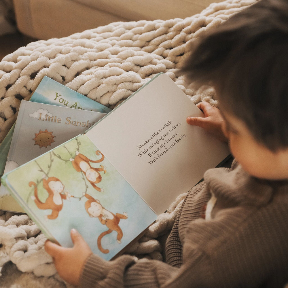 Child reading Critter Crews Board Book featuring illustrated monkeys swinging in trees.