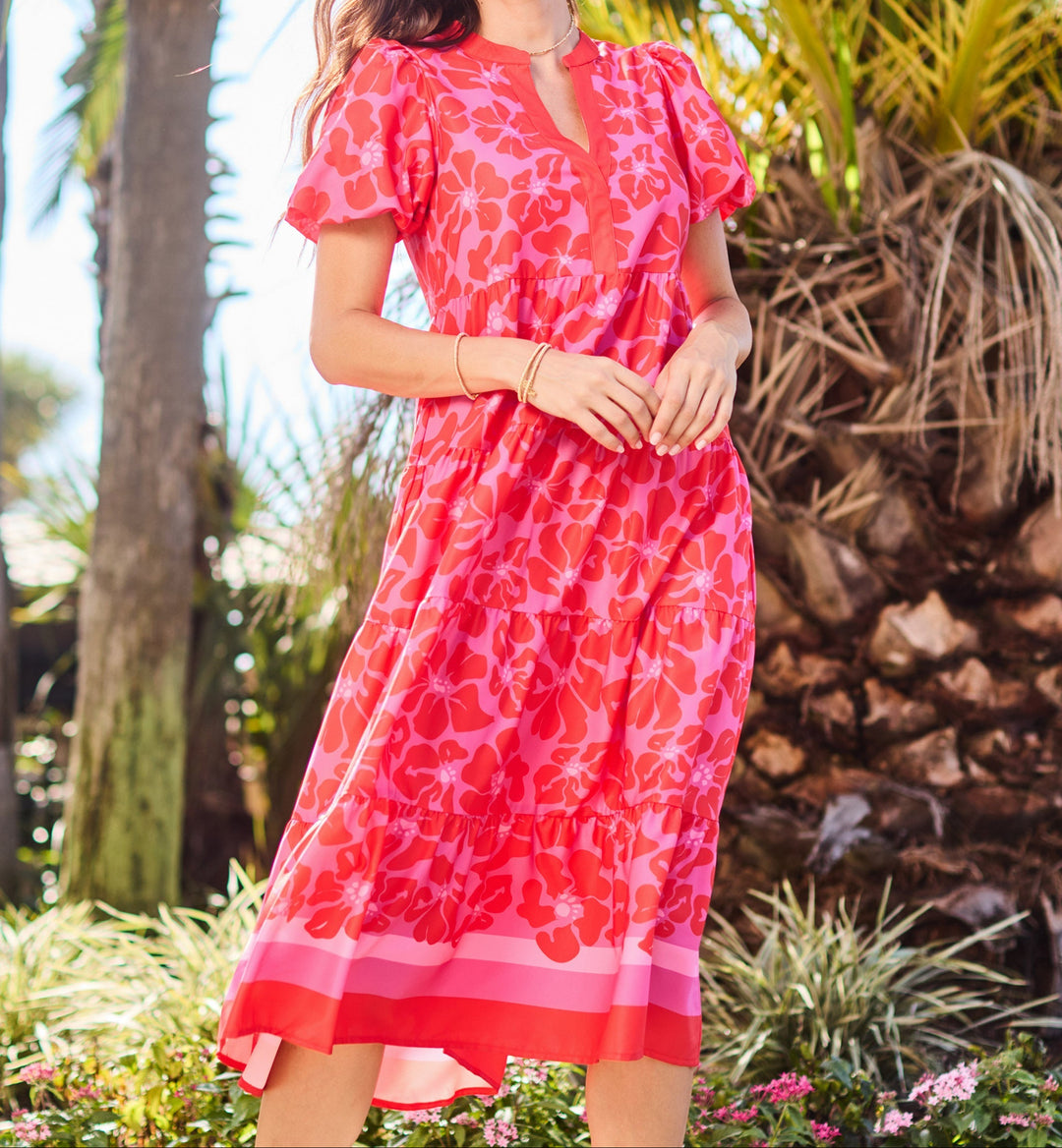 Woman wearing pink floral midi dress with short sleeves in tropical setting