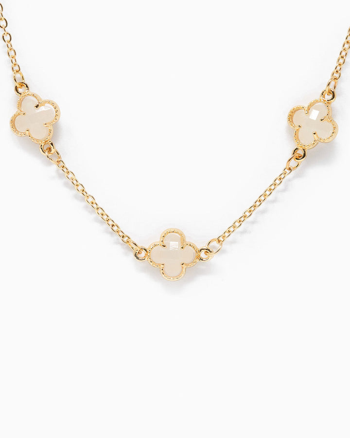 Gold chain station necklace featuring three white clover-shaped pendants with mother of pearl inlay.