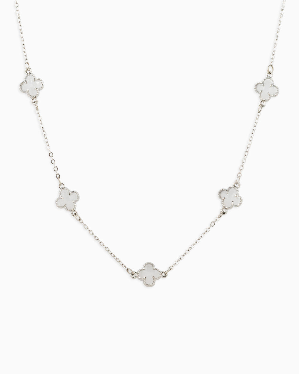 Silver station necklace featuring five white clover-shaped pendants on a delicate chain.