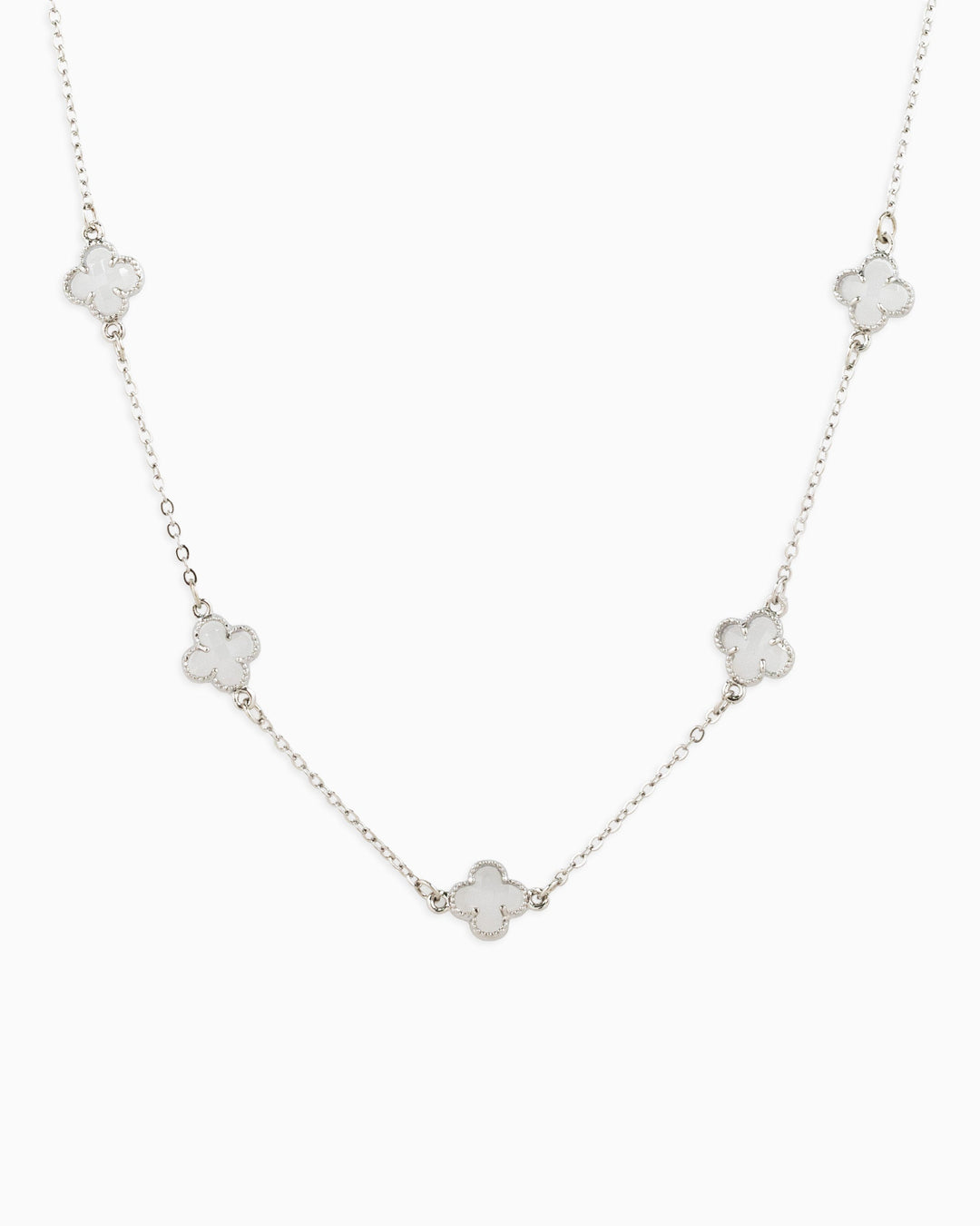 Silver station necklace featuring five white clover-shaped pendants on a delicate chain.