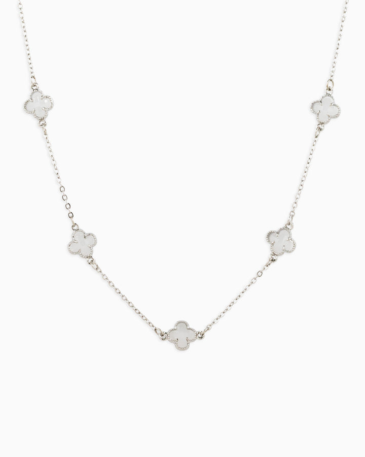 Silver station necklace featuring five white clover-shaped pendants on a delicate chain.
