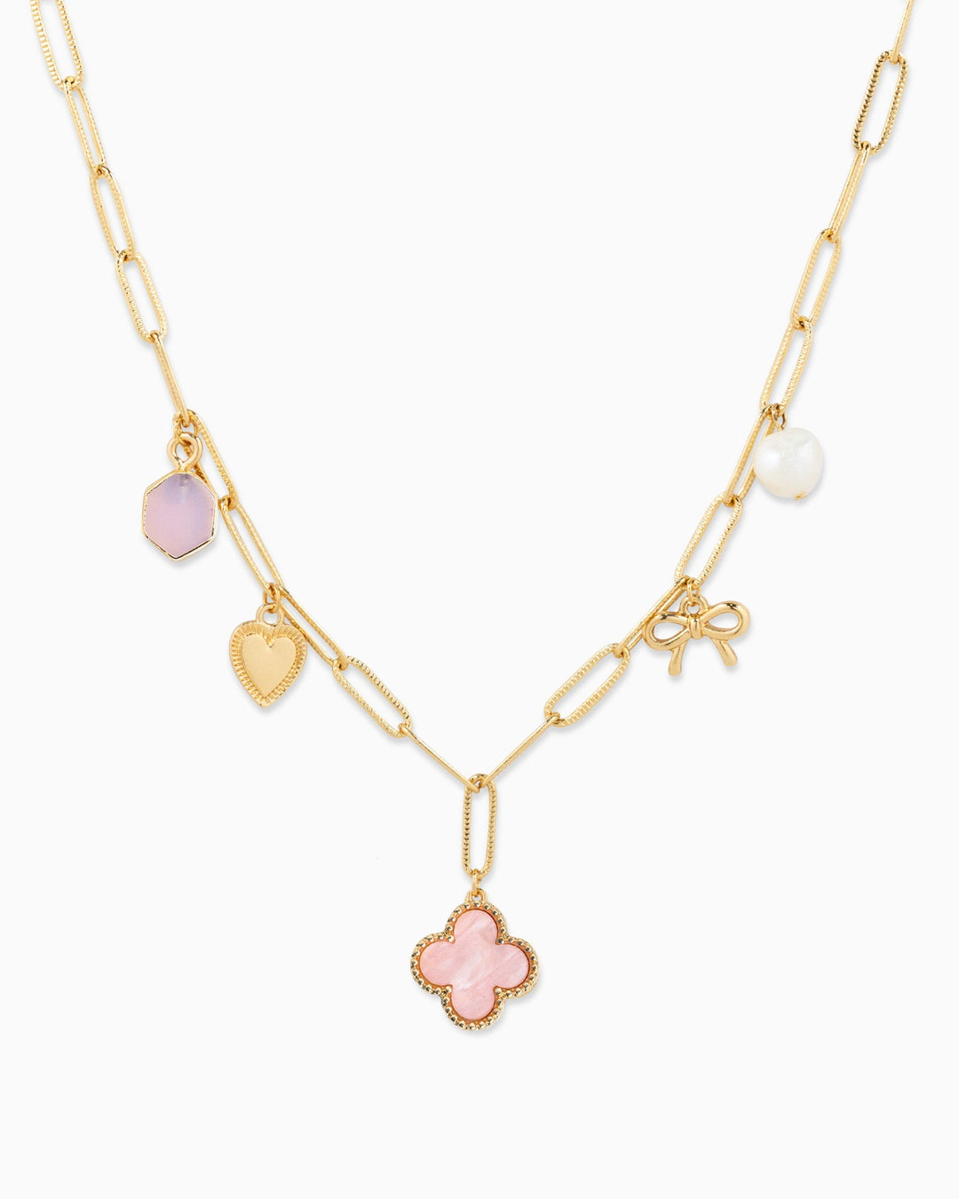Gold paperclip chain necklace with pink clover, heart, bow, pearl, and hexagon charms.