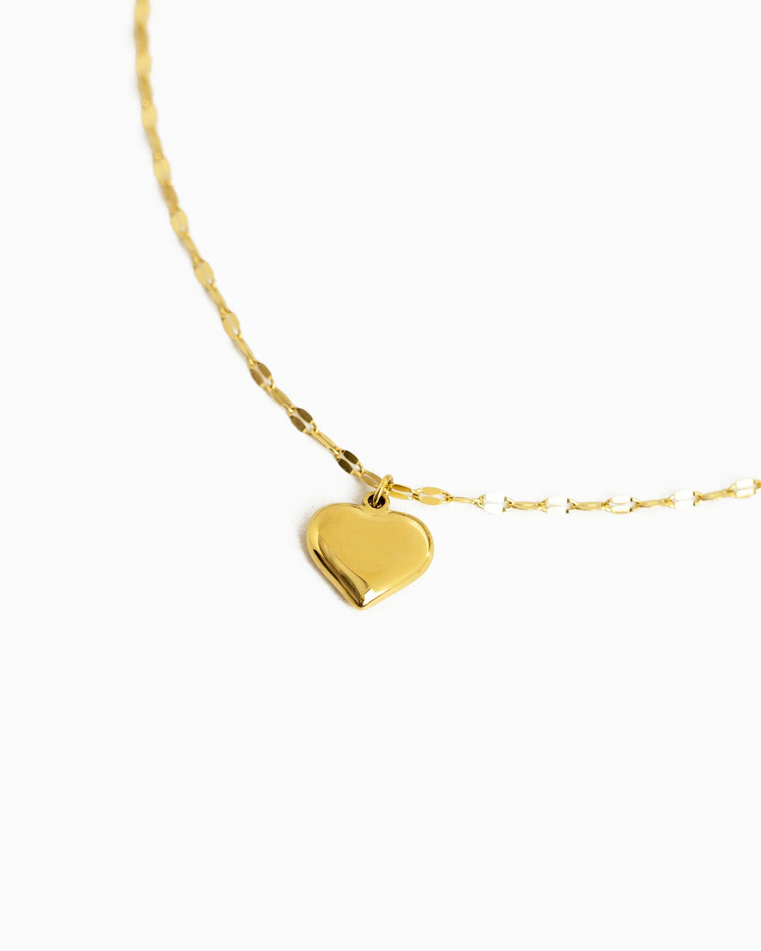 Gold stainless steel puffy heart pendant necklace with delicate chain on white background.
