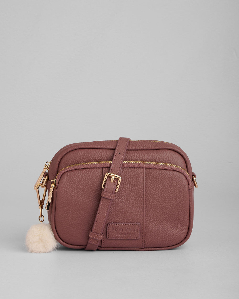 Dusty rose crossbody bag with gold hardware and white pom pom charm