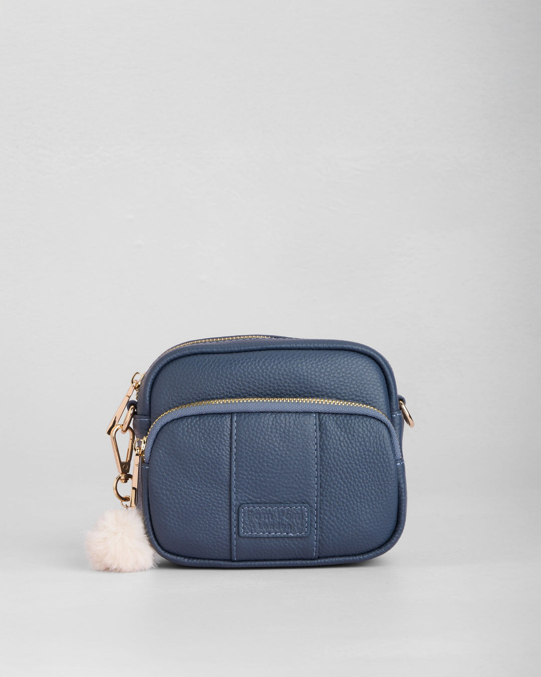 Slate blue leather mini crossbody bag with gold hardware and white pom pom charm