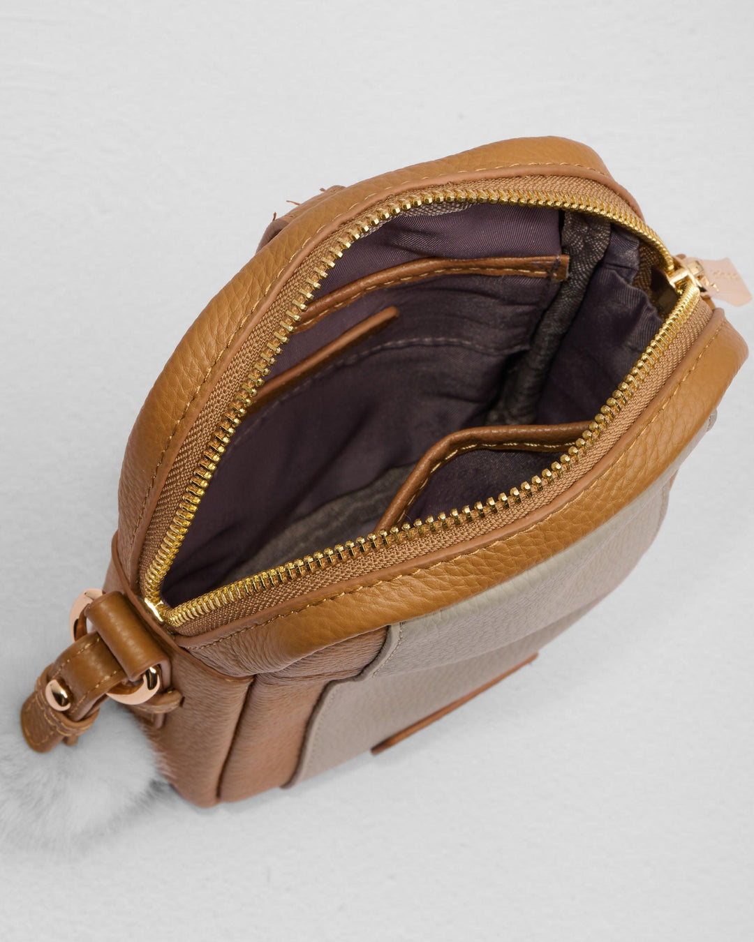 Brown leather crossbody phone bag with gold zipper and adjustable strap, interior view shown