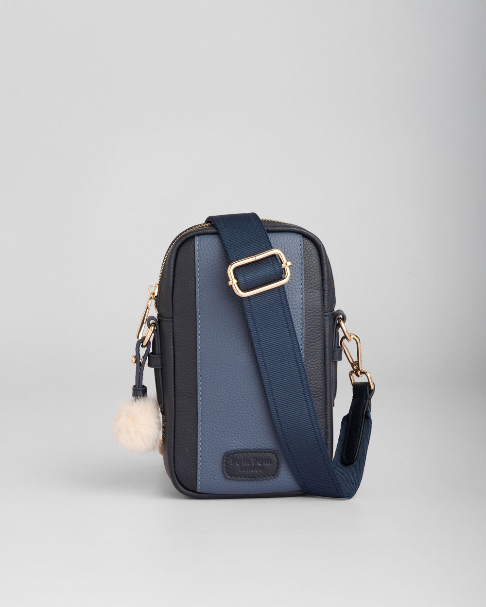 Navy and gray crossbody phone bag with adjustable strap and pom pom charm