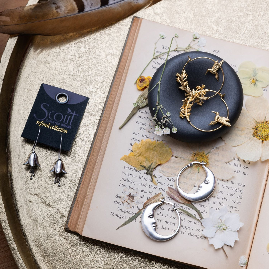 Scout Refined Icon Moon Hoop silver earrings with crescent moon face detail displayed on book
