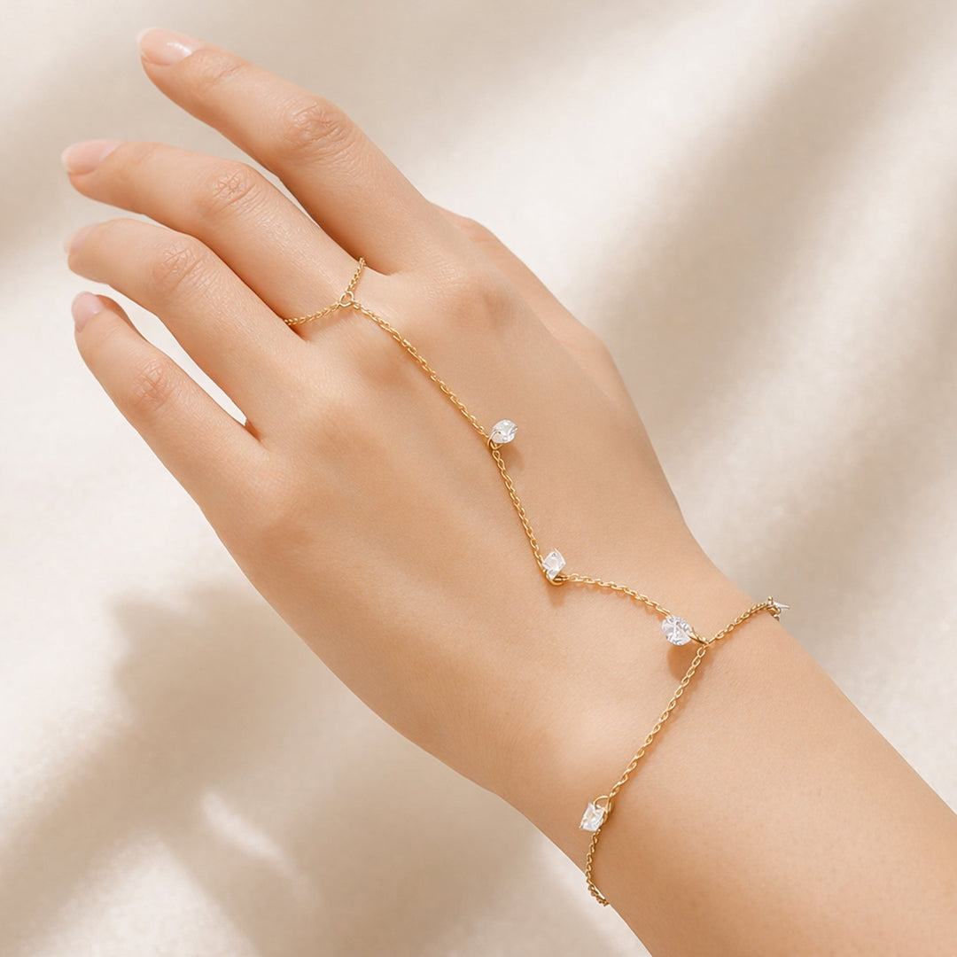 Gold hand chain bracelet with crystal accents connecting wrist to finger on a model