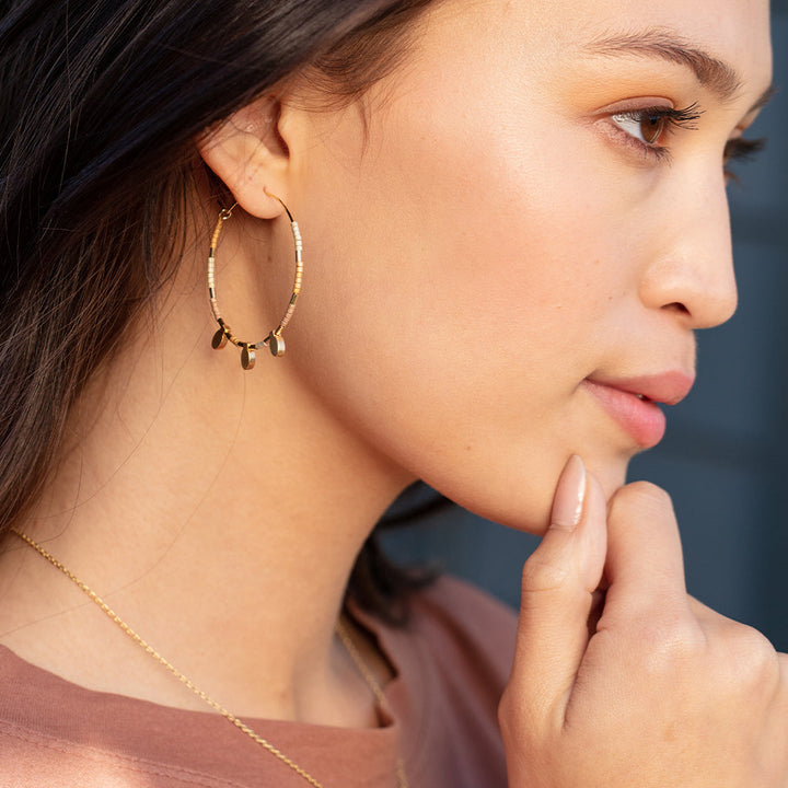 Model wearing Scout Chromacolor Miyuki large gold and white beaded hoop earrings