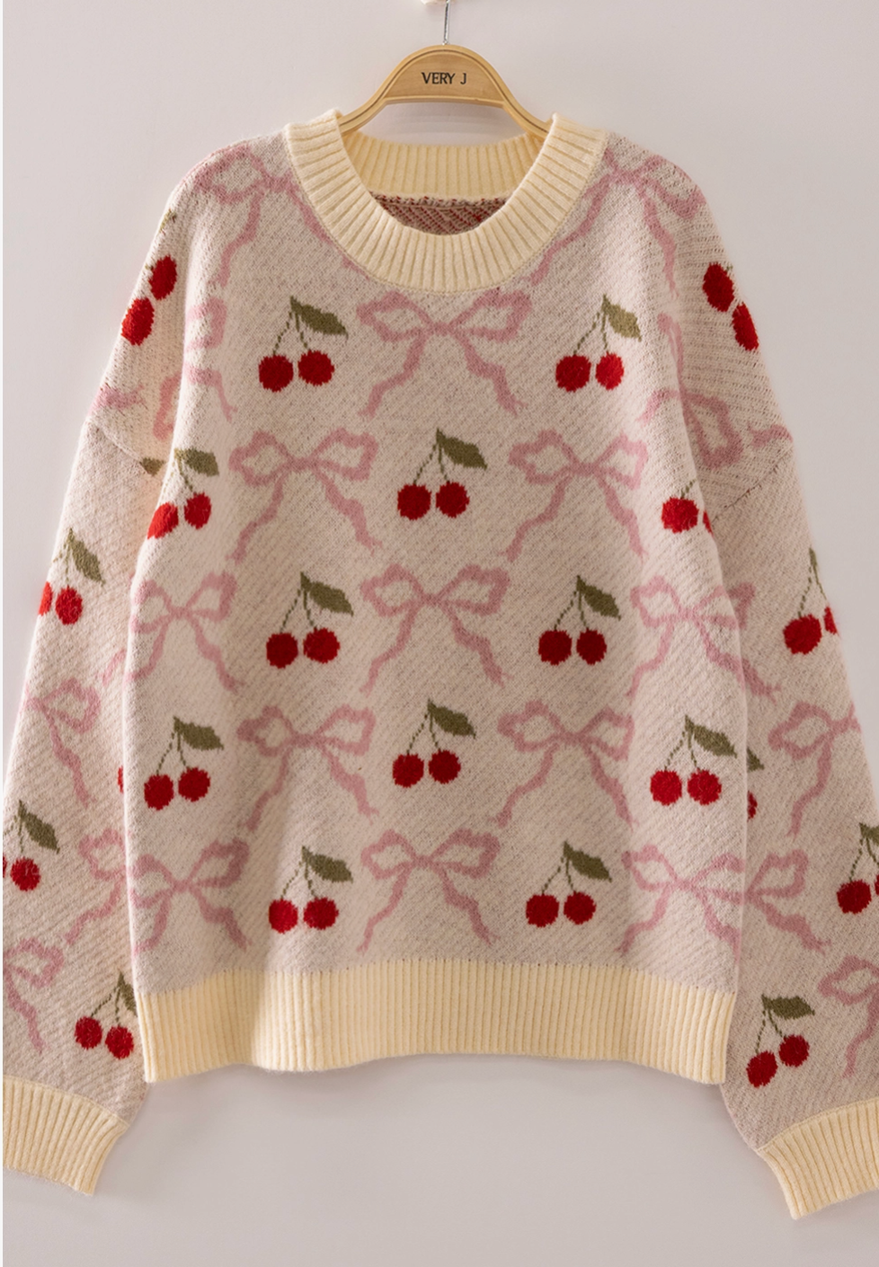 Cream knit sweater with red cherry and pink bow jacquard pattern, ribbed trim
