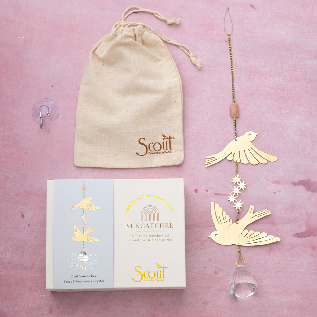 Scout brass bird suncatcher with crystal prism and packaging on pink background