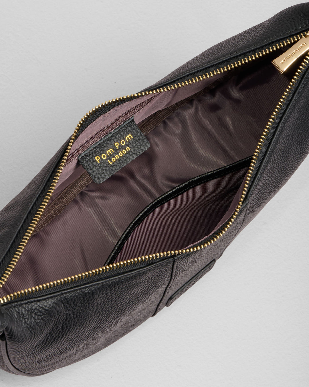 Black Pom Pom London Sutton Sling Bag opened showing interior compartments and gold zipper