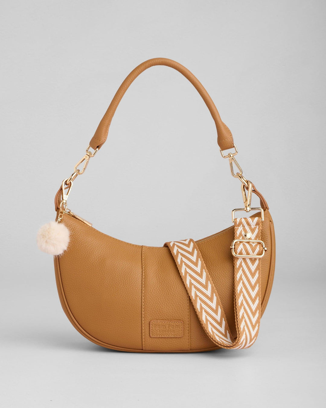 Tan leather Sutton Sling Bag with chevron strap and pom pom detail